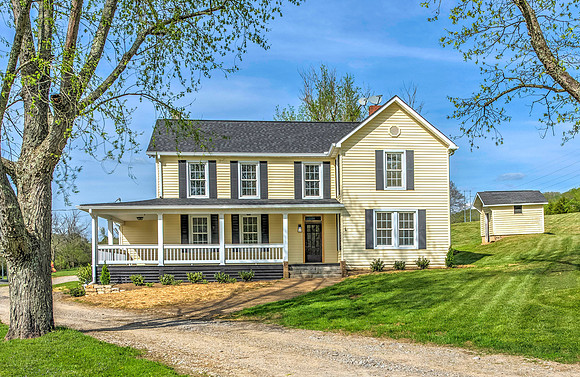 yellow two story farm house with covered porch in clinton, tn
